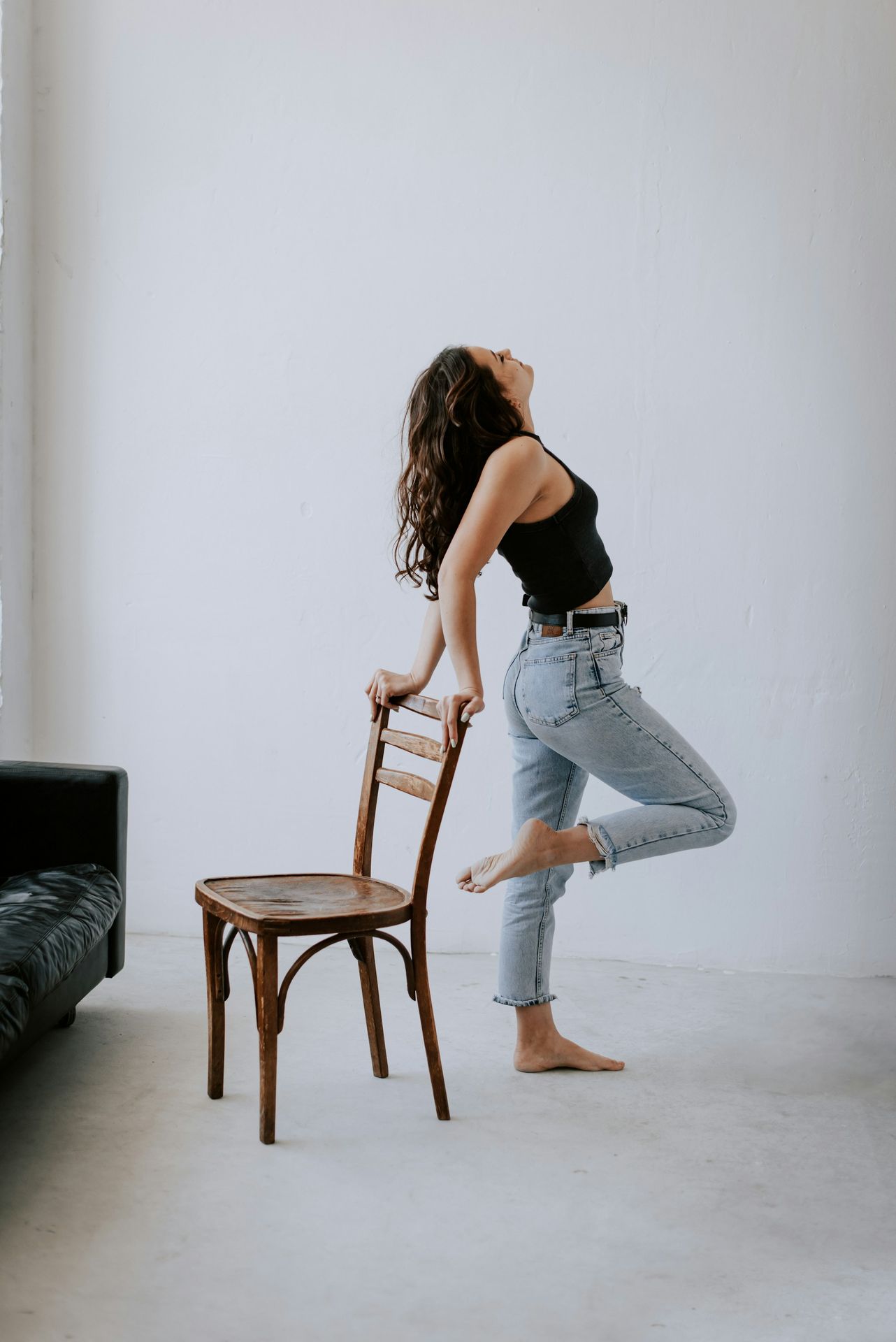 a woman standing next to a wooden chair